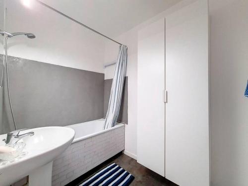 une salle de bain blanche avec un lavabo et une douche dans l'établissement appartement accès direct mer classé 3*, à Cabourg
