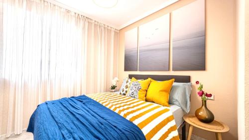 Apartamento a 3 min de la playa في توريفايجا: غرفة نوم بسرير مع وسائد زرقاء وصفراء