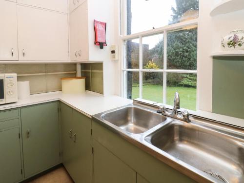 a kitchen with a stainless steel sink and a window at Cedars in Penrith