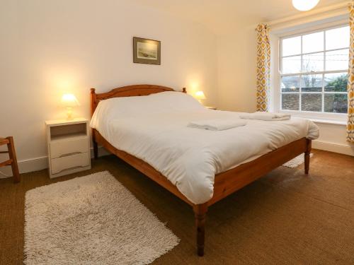 a bedroom with a large bed with white sheets and a window at Cedars in Penrith