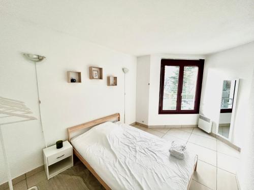 a white bedroom with a bed and a window at Chambre proche de Genève in Annemasse