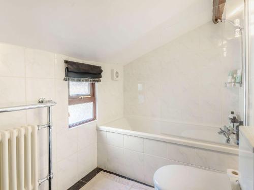 a white bathroom with a tub and a toilet at Mulberry Cottage in Bakewell