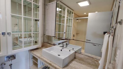 a white bathroom with a sink and a mirror at Amplo apartamento 03 dorm Centro de Gramado in Gramado
