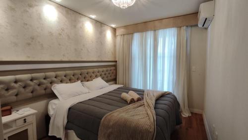 a bedroom with a large bed with a large window at Amplo apartamento 03 dorm Centro de Gramado in Gramado