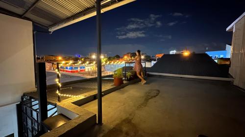 SJO Oasis Hostel في سان خوسيه: a woman walking on the roof a building at night