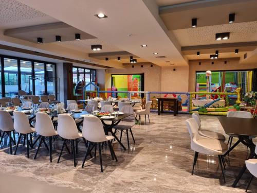 een restaurant met tafels en stoelen en een speeltuin bij Hotel Angro Palace in Kavadarci