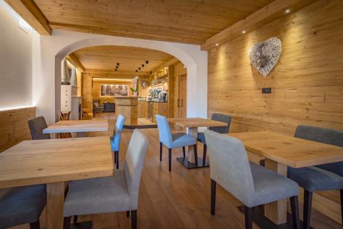 restauracja z drewnianymi ścianami oraz drewnianymi stołami i krzesłami w obiekcie Albergo Cavallino w mieście Sappada