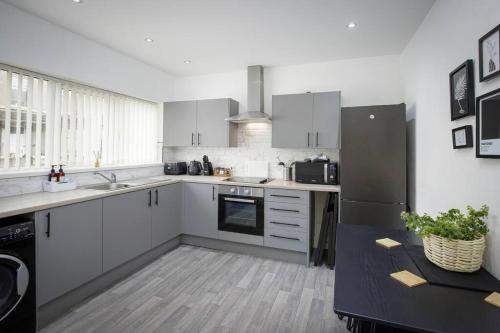 a kitchen with white cabinets and a black refrigerator at Standout 2 Bed House close to Blackpool Promenade in Blackpool