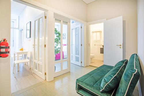 a living room with a green couch and a bathroom at Alegria Colour Apartments in Porto