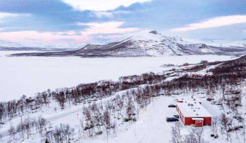 een rode schuur in de sneeuw met een berg bij Hostel Saana in Kilpisjärvi