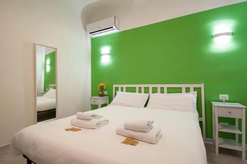 フィレンツェにあるIl Vagello B&Bの緑の壁と白いベッドが備わるベッドルーム1室