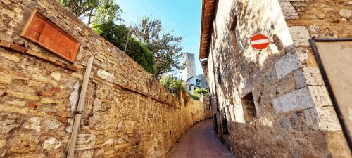 an alley in an old building with a sign on it at Casa nel centro storico in San Gimignano