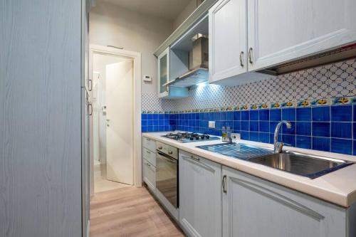 熱那亞的住宿－Cuore blu，厨房配有水槽和蓝色的瓷砖墙壁