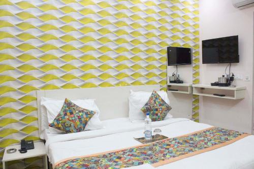 a room with a bed and a yellow and white wall at JSB HOTEL in Faridabad