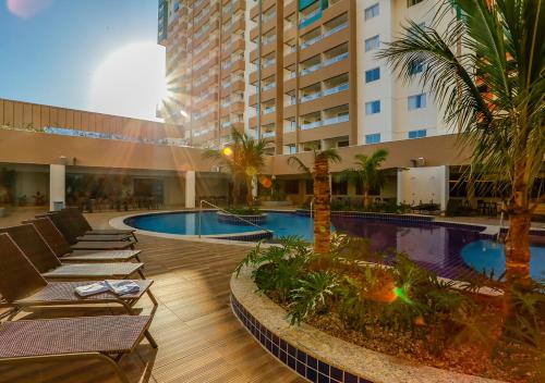 um hotel com piscina e palmeiras e um edifício em Enjoy Olimpia Park Resort em Olímpia
