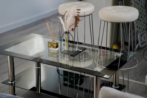 einem Glastisch mit zwei Hockern und einer Fernbedienung in der Unterkunft Luxury Two Bedroom Apartment Southsea in Portsmouth