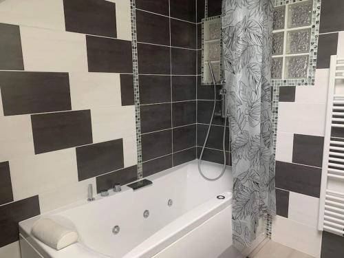 een wit bad in een badkamer met zwarte en witte tegels bij Appartement moderne in Remiremont