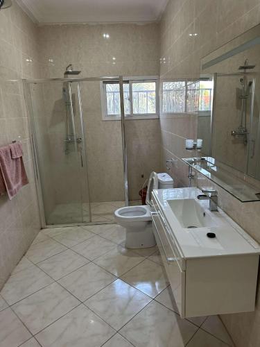 y baño con ducha, aseo y lavamanos. en Luxury 2 bedroom flat KerrSerign en Banjul