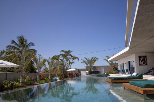 a pool at a resort with chairs and umbrellas at The View - Adults Only Resort in Pipa