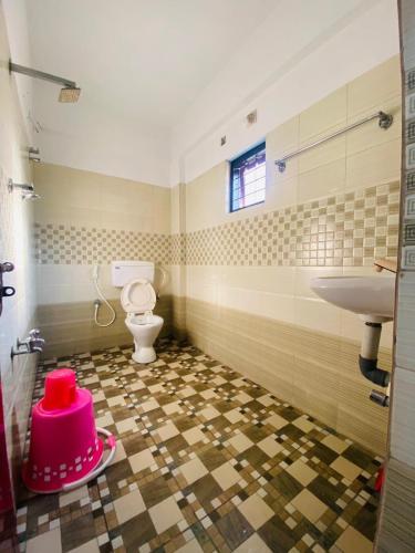 a bathroom with a toilet and a pink hat on the floor at Green Line Homestay in Vythiri