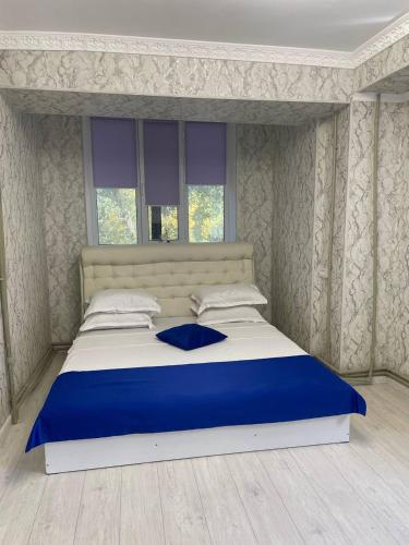 Una cama azul y blanca en un dormitorio en Французский дом 47 en Shymkent