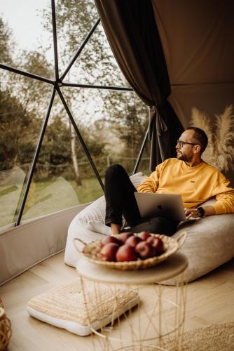 a man laying on a bed with a laptop and a plate of fruit at Czorsztyn Glamp in Maniowy