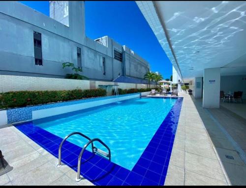 uma grande piscina azul ao lado de um edifício em Imperial Tambau By Loui em João Pessoa