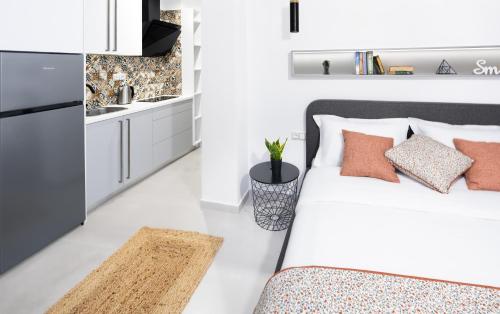 a white bedroom with a bed and a kitchen at Ando’s Cozy Studio Apartment in Athens