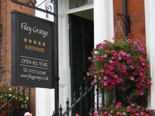 een bord aan de zijkant van een gebouw met bloemen bij Filey Grange in Filey