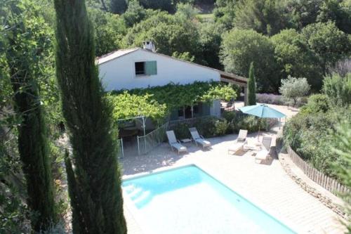 a house with a swimming pool with chairs and an umbrella at Aux Dentelles in La Roque-Alric