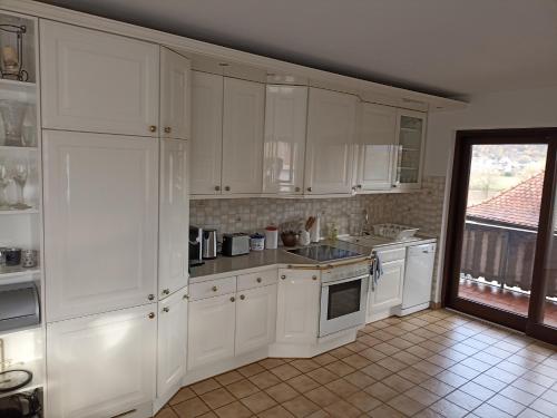 uma cozinha branca com armários brancos e uma janela em Ferienwohnung Marell em Großwallstadt