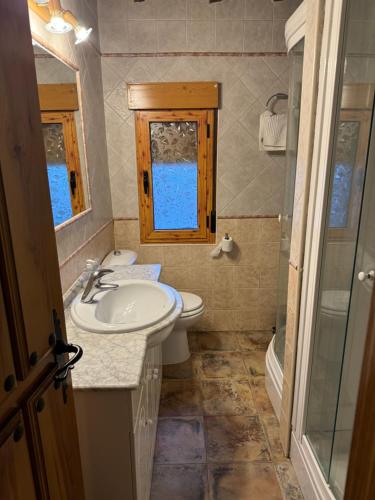 ein Badezimmer mit Waschbecken und Toilette und einem Fenster in der Unterkunft Casa Rural El Medico in Serradilla del Arroyo
