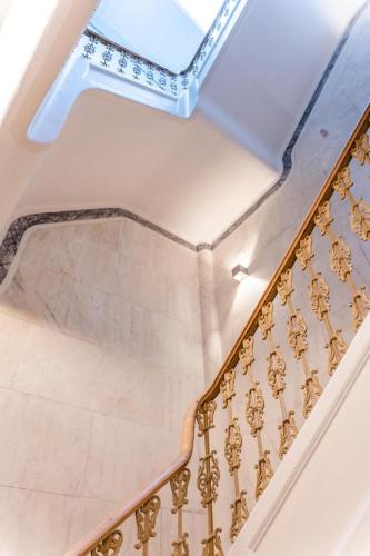 a staircase with a gold railing in a building at Guest House - Palácio Diana in Évora
