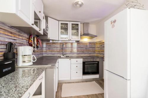 a kitchen with white cabinets and a refrigerator at Holiday Home Svjetlana in Risika