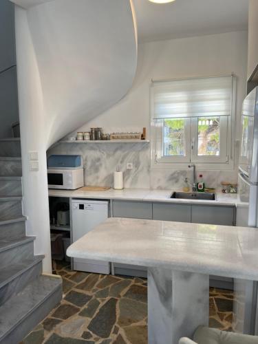 a white kitchen with a sink and a counter at Sea views - Marble Palace - 2 floors in Tinos