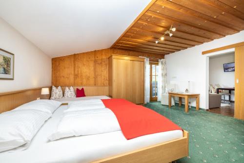 Schlafzimmer mit einem großen Bett mit einem Kopfteil aus Holz in der Unterkunft Pension Kreuzer in Flachau
