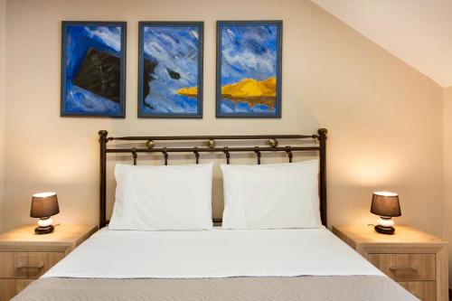 a bedroom with a bed with three paintings on the wall at Villa Murtal in Gerani