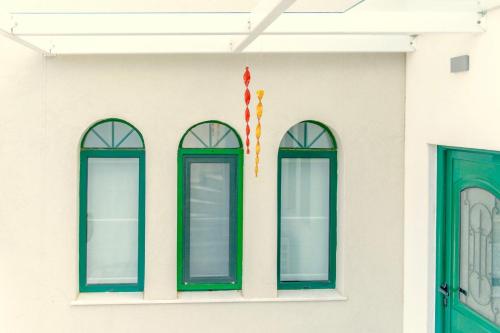 a white building with green windows and a flag at Villa Murtal in Gerani