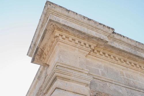 un edificio de piedra alto con columna de aocrativeieval en La volpe e l'uva Dimore, en Montescaglioso