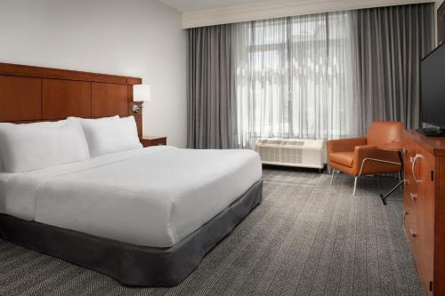 a hotel room with a bed and a desk and a television at Courtyard Jacksonville Flagler Center in Jacksonville