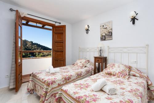 two beds in a room with a window at Villa Flower in Cómpeta