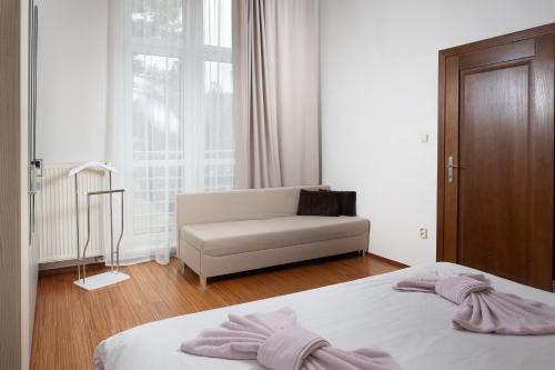a bedroom with a bed and a couch and a window at Apartments Tatra Olla - Tatranská Lomnica in Tatranská Lomnica