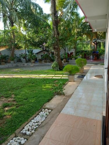 a garden with a walkway and a lawn with palm trees at The River Villa in Talpe