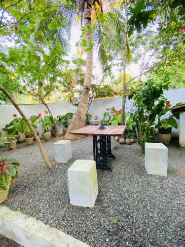 a picnic table in a courtyard with trees and plants at The River Villa in Talpe