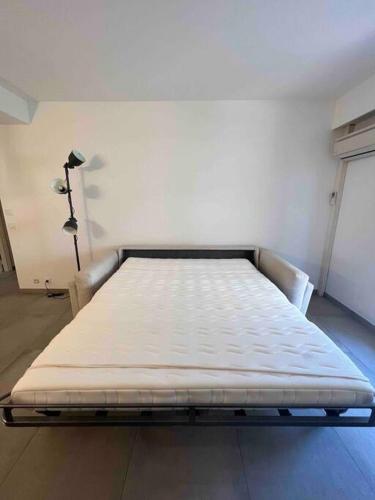 un lit vide dans une pièce avec une lampe dans l'établissement Studio proche plage et vieil Antibes + Parking, à Antibes
