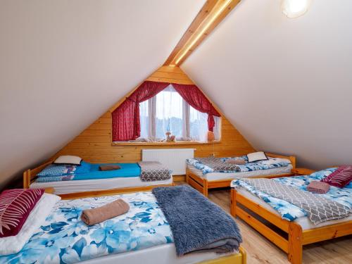 a attic room with three beds and a window at Gazdówka na Mosornym Groniu in Zawoja
