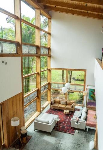 a living room filled with furniture and a large window at Jungle Haven Ocean Front Eco Villa On Fruit Farm in Pahoa