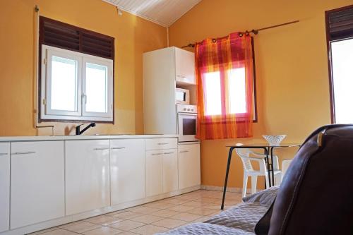 una cocina con armarios blancos y una mesa en una habitación en Loca Vacances, en Sainte-Anne