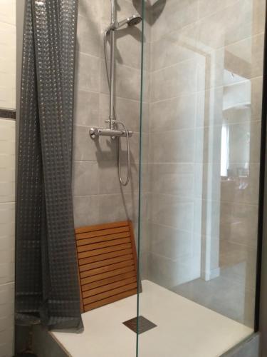 a shower with a glass door and a wooden bench in a bathroom at "Air d'Antan"-Meublé de Tourisme 3 étoiles -Résidence "Les Logis de Béziers"-Garage optionnel-Cœur de ville-Plages à 16km ! in Béziers