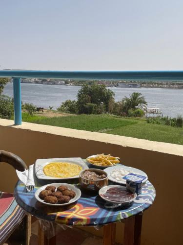 a table with food on a balcony with the beach at Nubian Holiday House Aswan in Aswan